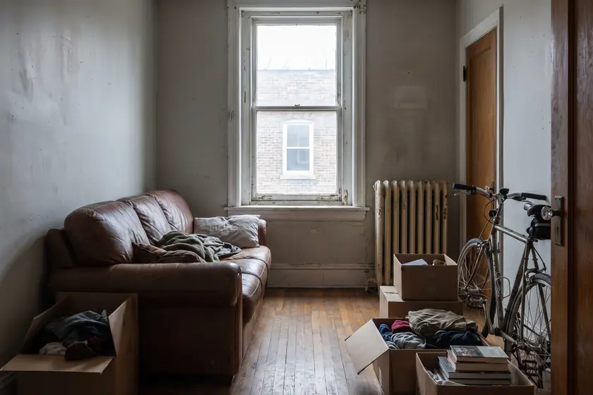 A modest rental apartment interior with a radiator under a tall sash window